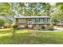Charming two-story home with a mix of brick and green wood, surrounded by mature trees and green lawns at 2712 Pebblebrook Dr, Sanford, NC 27330