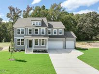 Beautiful two-story home featuring a gray exterior, a welcoming front porch, and an attached two-car garage at 380 Shelby Meadow Ln, Angier, NC 27501