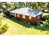 Charming brick home with a well-manicured lawn and mature trees providing ample shade at 452 N Main St, Wendell, NC 27591