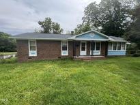 Charming brick home featuring a covered front porch, updated trim, and freshly mowed lawn at 503 Adams St, Henderson, NC 27536