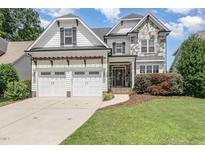 Charming two-story home featuring a stone facade, a three-car garage, and a well-manicured lawn at 5629 Clearsprings Dr, Wake Forest, NC 27587