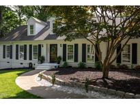 Charming home featuring a meticulously landscaped front yard with lush green grass, plants and a paved walkway to the front door at 8604 Timberwind Dr, Raleigh, NC 27615