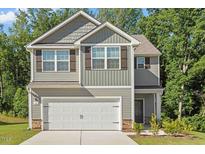 Charming two-story home with gray siding, stone accents, and a two-car garage at 94 Taverners Ln, Angier, NC 27501