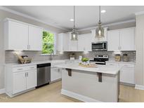 Bright kitchen features white cabinets, stainless steel appliances, and a center island perfect for meal prep and entertaining at 141 Alden Way, Angier, NC 27501