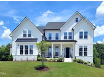 Stunning two-story white home boasting a well-manicured lawn and inviting curb appeal under a bright, partly cloudy sky at 1425 Sierra Glen Cir, Apex, NC 27502