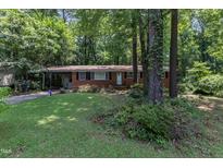 Charming brick home featuring a well-maintained lawn and mature trees, providing a serene and inviting curb appeal at 1500 Lakeside Dr, Garner, NC 27529