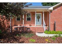 Charming brick home featuring a welcoming front porch with a light blue door and a decorative wreath at 1975 Oakridge Duncan Rd, Fuquay Varina, NC 27526