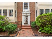 Charming brick building with white trim, a glass front door, and professional landscaping creates an inviting entrance at 235 Mccauley St # D, Chapel Hill, NC 27516