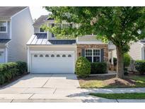 Charming home featuring a stone facade, a two-car garage, and a beautifully landscaped front yard with mature trees at 238 Royal Tower Way, Cary, NC 27513