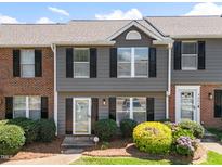 Charming townhome featuring a glass front door, black shutters, and manicured landscaping at 4649 Pine Trace Dr, Raleigh, NC 27613