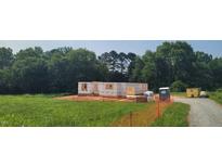 Framed home under construction showcasing the initial structure and design in a grassy lot surrounded by trees at 5545 Silk Hope Gum Springs Rd, Siler City, NC 27344