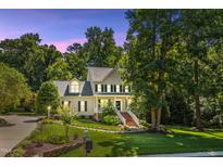 Inviting two-story home with manicured lawn, mature trees, and charming front porch at twilight at 5940 Dahlberg Dr, Raleigh, NC 27603