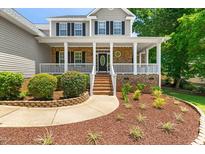 Charming brick home featuring a welcoming front porch with white columns and meticulously maintained landscaping at 63 Majestic Oak Dr, Garner, NC 27529