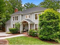 Charming gray two-story home with a welcoming front porch and manicured landscaping surrounded by mature trees at 105 Jolyn Pl, Chapel Hill, NC 27517