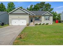 Charming single-story home with a well-manicured lawn and an attached two-car garage at 115 Snowy Orchid Ln, Smithfield, NC 27577
