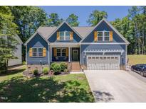 Charming two-story home with blue siding, a two-car garage, and a well-manicured front yard at 1176 Sagamore Dr, Louisburg, NC 27549