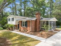 Charming home with brick chimney, screened porch, and well-manicured lawn, shaded by mature trees at 1205 Willow Dr, Chapel Hill, NC 27517