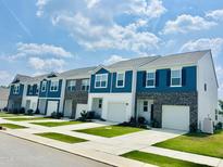 Charming townhouses featuring blue and white exteriors with well-maintained landscaping and individual garages at 139 N Chubb Rdg, Wilson's Mills, NC 27520