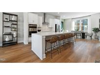 Modern kitchen features a large island with seating, stainless steel appliances, and hardwood floors at 1501 Village Hall Ln # 38, Wake Forest, NC 27587
