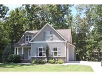 Charming home with gray siding, stone accents, and lush landscaping in a serene, tree-lined setting at 2471 Golden Forest Dr, Franklinton, NC 27525