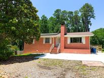 Charming red brick home with a brick chimney, white trim, and a large front yard tree at 3323 Baugh St, Raleigh, NC 27604