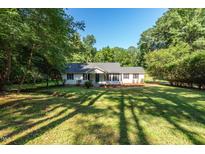 Charming single-story home with a lush green front yard and mature trees offering plenty of shade on a sunny day at 514 Lipscomb Grove Church Rd, Hillsborough, NC 27278