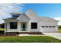 Charming single-story home with a white exterior, teal front door, and well-maintained lawn at 5491 Silk Hope Gum Springs Rd, Siler City, NC 27344
