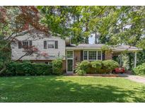 Charming two-story home featuring a lush green lawn, brick accents, and a convenient covered carport at 612 Locust Ln, Raleigh, NC 27603