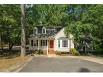 Charming home featuring a red door, dormer windows, and a cozy front porch surrounded by lush trees at 616 Cross Timbers Dr, Durham, NC 27713