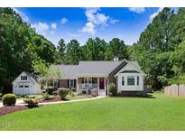 Charming home with a well-manicured lawn and inviting curb appeal, framed by mature trees and a detached garage at 10031 Old Middlesex Rd, Middlesex, NC 27557