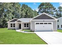 Charming one-story home with a manicured lawn and attached two car garage at 125 Davis St, Louisburg, NC 27549