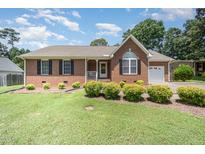 Charming brick home featuring manicured landscaping, a manicured lawn, and an attached garage in a suburban setting at 1822 Atterbury Ln, Durham, NC 27712
