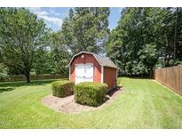 Exterior view of a barn style storage shed with double doors surrounded by green lawn and manicured landscaping at 1822 Atterbury Ln, Durham, NC 27712