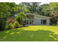 Beautiful home with a modern design, full front windows, landscaped lawn, and mature trees at 1908 S Lakeshore Dr, Chapel Hill, NC 27514