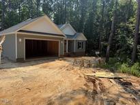 Charming single-story home featuring an attached garage and a beautifully wooded lot at 211 Rollins Acres Ln, Lillington, NC 27546