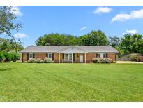 Charming brick home with a manicured lawn, lush landscaping, and a welcoming front porch at 2119 Northcrest Dr, Elon, NC 27244