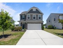 Charming two-story home featuring gray siding, stone accents, and a two-car garage with a concrete driveway at 22 Combine Trl, Benson, NC 27504