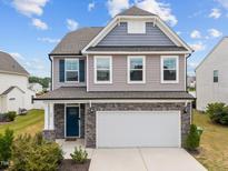 Charming two-story home featuring a stone-accented garage and welcoming front porch at 22 Combine Trl, Benson, NC 27504