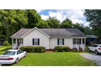 Charming single-story home with well-maintained lawn and landscaping under a partly cloudy sky at 308 E Gilbreath St, Graham, NC 27253