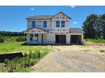 New two-story home showcasing a two-car garage under construction with an unfinished lawn and pleasant tree line at 3895 Josiah Ct, Nashville, NC 27856