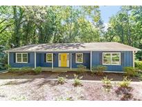 Charming blue home featuring a bright yellow front door, complemented by lush greenery for added privacy at 5124 Lazywood Ln, Durham, NC 27712