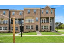 Brick townhomes feature a manicured lawn, neutral paint and charming black trimmed windows and doors at 529 Forestville Rd, Wake Forest, NC 27587
