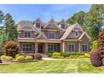 Stunning stone home with manicured lawn, dormer windows, and lush landscaping at 1009 Margarets Ln, Raleigh, NC 27614