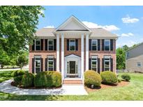 Stunning brick home with white columns, black shutters, and a well-manicured front lawn at 318 Riggsbee Farm Dr, Cary, NC 27519
