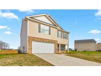 Two-story home features a brick and vinyl exterior with an attached garage and a long concrete driveway at 119 Leven Dr, Gibsonville, NC 27249