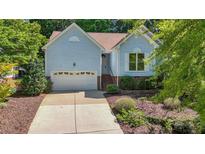 Charming one-story home featuring light blue siding, well-manicured landscaping, and an attached garage at 125 Chimney Rise Dr, Cary, NC 27511