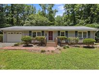 Charming single-story home featuring a brick pathway, well-manicured lawn, and an inviting red front door at 18 Red Pine Rd, Chapel Hill, NC 27516