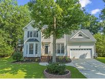 Charming two-story home featuring a well-manicured lawn and attached two-car garage at 208 Holly Green Ln, Holly Springs, NC 27540