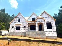 New home under construction with guard wrap and window openings, set on a beautiful wooded lot at 30 Cherry Bark Dr, Youngsville, NC 27596