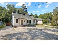 Charming white home with a cozy front porch and well-maintained gravel yard surrounded by mature trees at 606 E Club Blvd, Durham, NC 27704